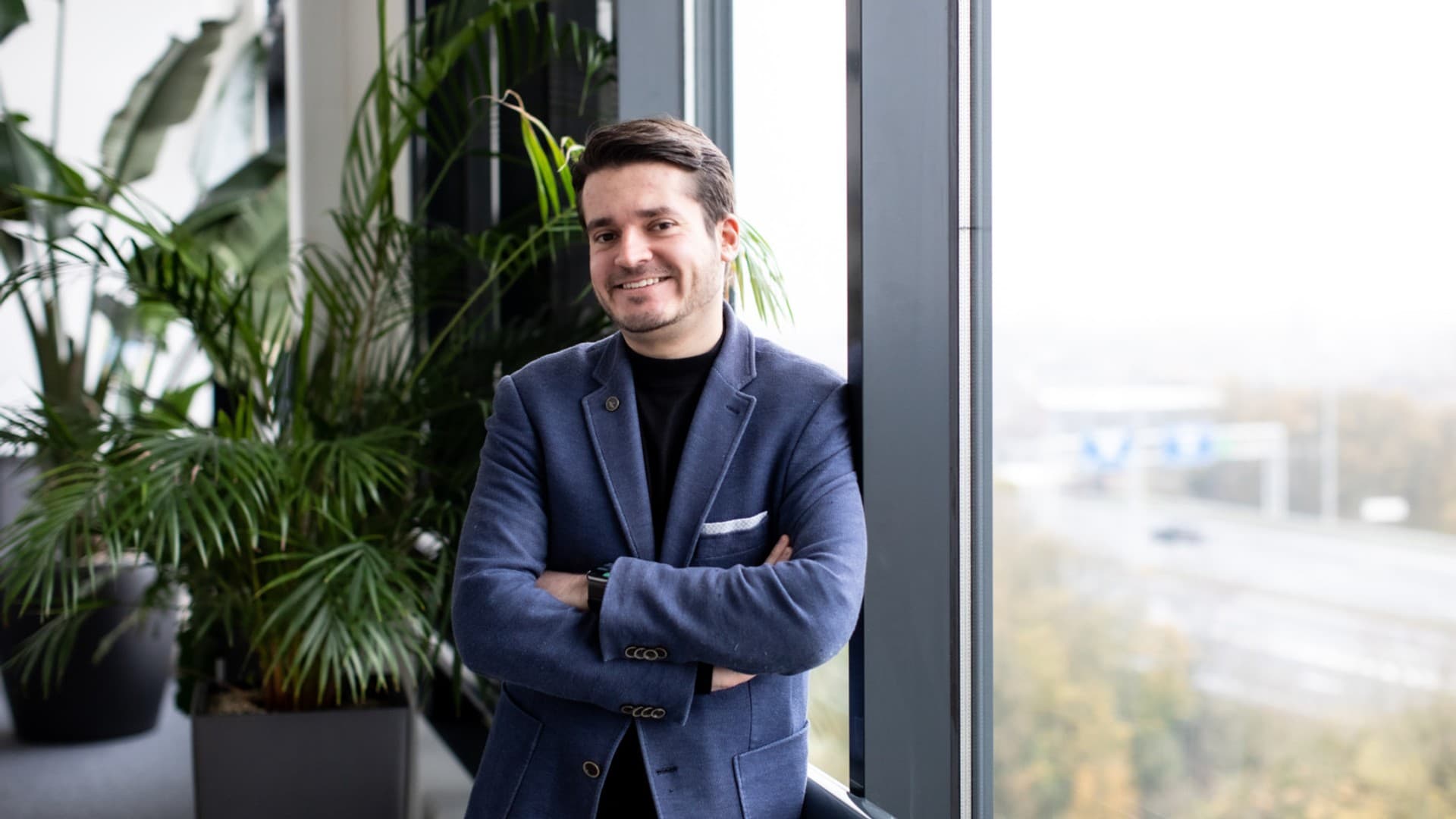 Arvid De Coster, CEO of WeGroup, smiling with his arms crossed at an office window
